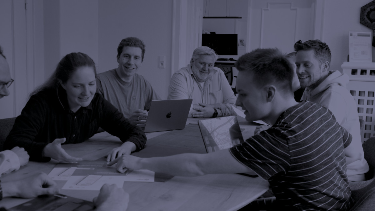 Menschen sitzen gemeinsam am Tisch und diskutieren.