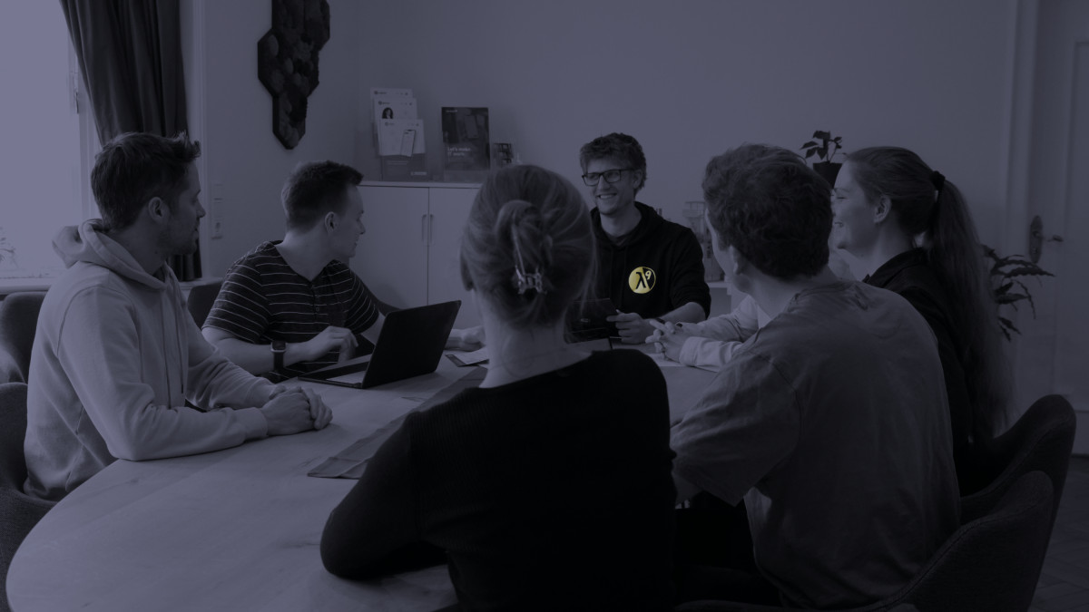 Personen der lambda9 tauschen sich am Meetingtisch aus.