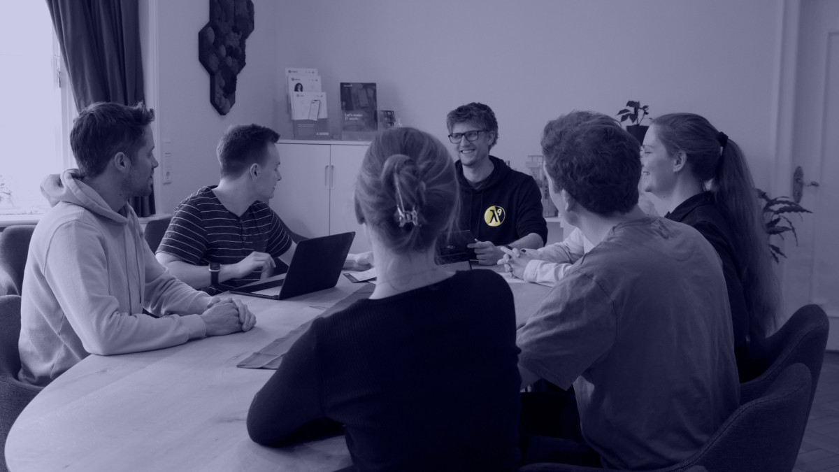 Personen der lambda9 tauschen sich am Meetingtisch aus.